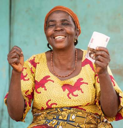 An excited elderly African woman outdoors holding money